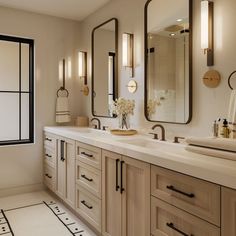 a bathroom with two sinks, mirrors and lights on the wall above them is shown