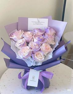 a bouquet of pink roses sitting on top of a white table next to a card