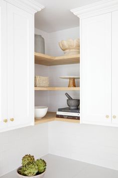 a white kitchen with open shelves and bowls on the counter