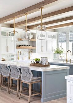 a kitchen with white cabinets and blue island in the center, surrounded by hanging glass globes