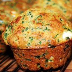 several muffins with cheese and spinach on a cooling rack in the oven