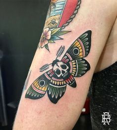 a woman's arm with a butterfly and skull tattoo on the left side of her body