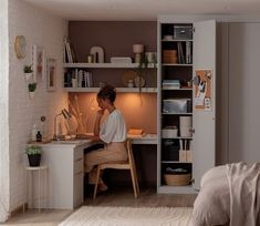 a woman sitting at a desk in front of a computer on top of a wooden table