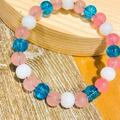 a close up of a bracelet with beads on a wooden table next to a piece of wood