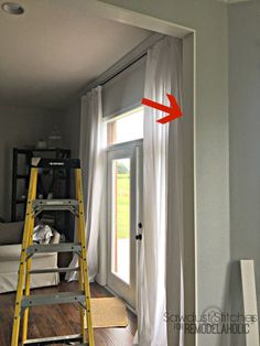 a ladder that is next to a window with curtains on it and a yellow ladder in front of the window