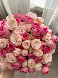 a person holding a bouquet of pink and white flowers