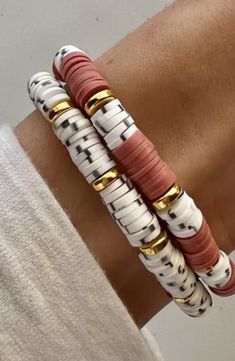 three bracelets are stacked on top of each other in different colors and shapes, with gold accents