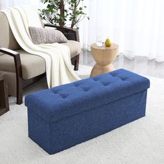 a blue ottoman sitting on top of a white rug next to a chair and table