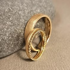 two gold rings sitting on top of a rock