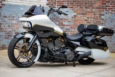 a white and black motorcycle parked in front of a brick wall