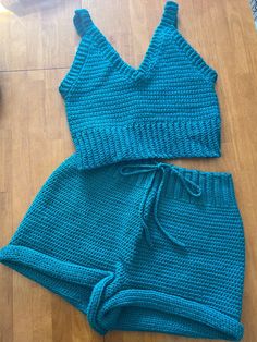 two pieces of blue knitted clothing sitting on top of a wooden floor