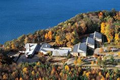 an aerial view of a building surrounded by trees with fall foliage on the ground and water in the background