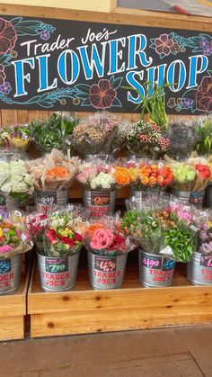 several buckets filled with different types of flowers on display at a farmer's market