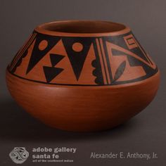 an orange and black vase sitting on top of a table