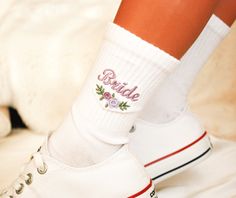 a person wearing white tennis shoes with embroidered socks