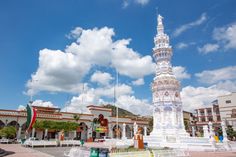 a tall white tower sitting in the middle of a park next to a building on a sunny day