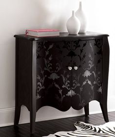 a black and white cabinet with two vases on it's side stand next to a zebra print rug