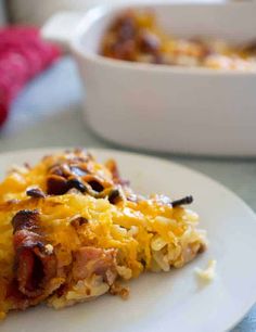 a slice of pizza on a white plate with cheese and meat toppings next to a casserole dish