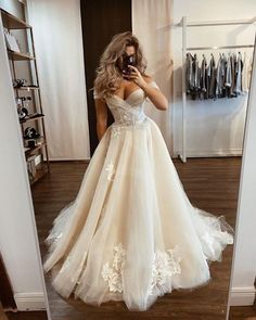 a woman in a wedding dress taking a selfie with her cell phone while standing in front of a mirror