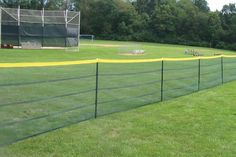 a baseball field with a fence on the grass and people in the dugout behind it