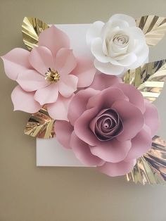 three paper flowers on a white card with gold foil leaves and one pink flower in the middle