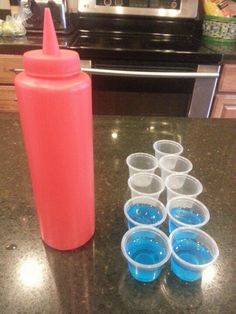 several cups and a bottle sitting on a counter top next to an oven with a microwave in the background