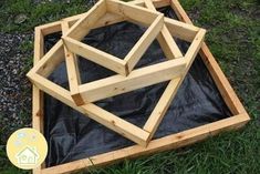 three wooden structures sitting in the grass on top of plastic tarp next to each other