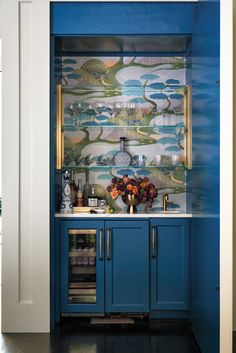 a kitchen with blue cabinets and wallpaper on the walls, along with a wine glass cabinet