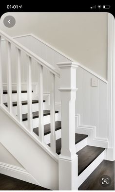 a white staircase with black carpet and wooden handrails in an empty room on the first floor