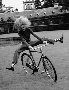 an old black and white photo of a woman on a bicycle