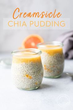 two jars filled with chia pudding on top of a white table next to an orange slice