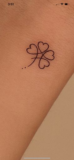 a small four leaf clover tattoo on the left side of the arm, with black ink