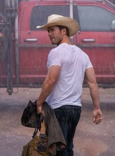 a man walking in the rain with his hat on