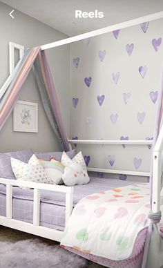 a child's bedroom with hearts painted on the walls and bedding in pastel colors