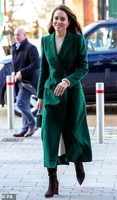 the woman is walking down the street wearing a green coat