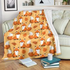 an orange and white blanket with foxes on it sitting next to a couch in a living room