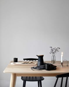 a wooden table topped with two vases filled with flowers next to candles and plates