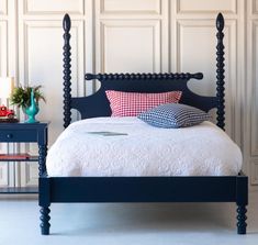 a bed with blue headboard and foot board in front of a white paneled wall