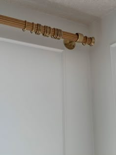 a close up of a curtain rod on a white wall in a room with a door