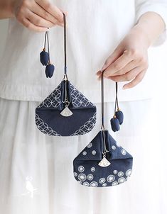 the woman is holding two small purses in her hands, both with tassels hanging from them