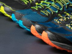 three pairs of running shoes are shown in this close - up photo, one is blue and the other is green