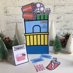 a table topped with lots of different types of cards and christmas tree decorations in front of a white brick wall