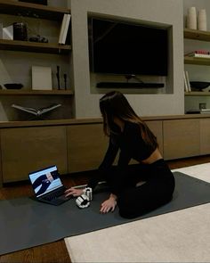 a woman is sitting on the floor with her laptop in front of her and she is looking at the screen