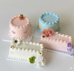 there are three cakes that have flowers on the top and one is pink, blue, and white