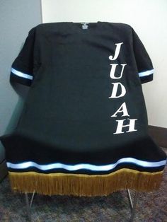 a black shirt with white letters and fringes on the back that says, judah