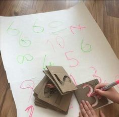 a child is drawing numbers on paper with crayons