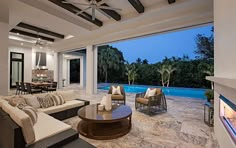 a living room filled with furniture and a fire place next to a swimming pool at night