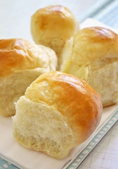 four rolls on a white plate sitting on a blue and white tablecloth