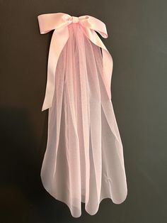 a pink veil hanging on the wall with a bow at the top and ribbon at the bottom