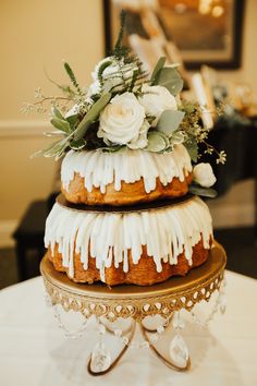 a three tiered cake with white icing and flowers on top is sitting on a table